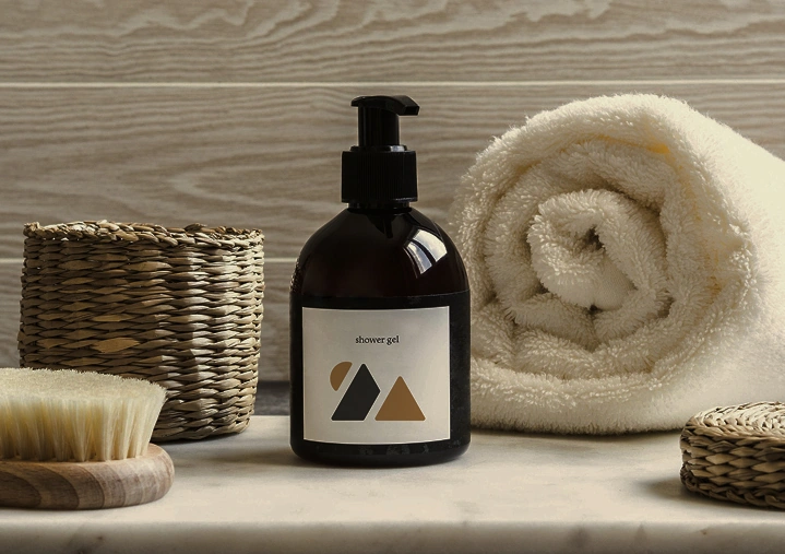 Shower gel bottle with towel and bath accessories on bathroom surface