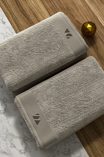 Folded towels on marble and wooden surface with minimalist branding