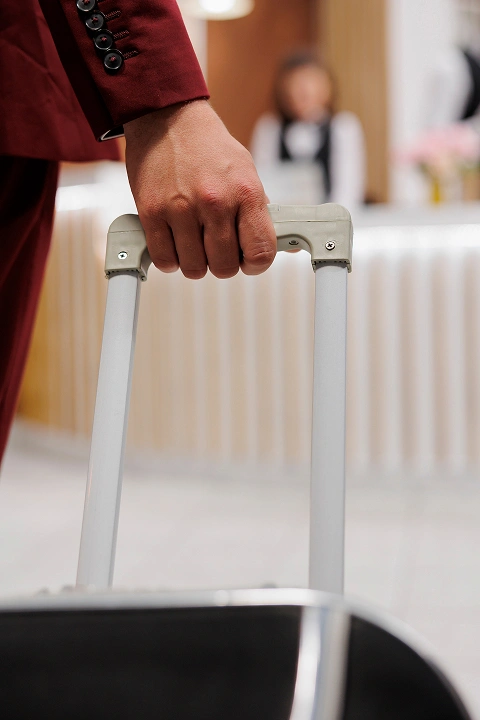 Guest’s hand holding a suitcase handle in front of the reception desk