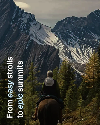 Person riding horse toward mountain peaks with forest landscape and scenic view