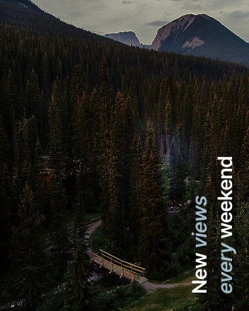 Forest mountain landscape with wooden bridge and “New views every weekend” text