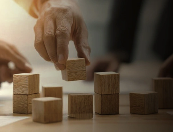 Hand placing wooden blocks, symbolizing building structure or strategy