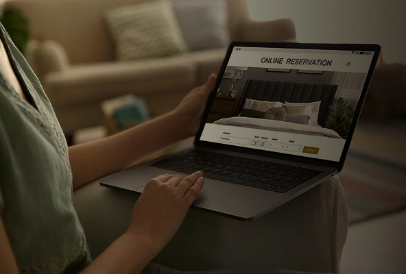 Person booking hotel room online on laptop at home