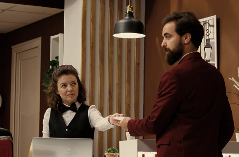 Hotel receptionist handing key card to guest at reception desk