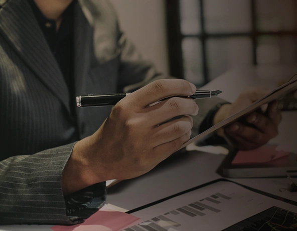 Businessperson reviewing documents and holding pen at desk