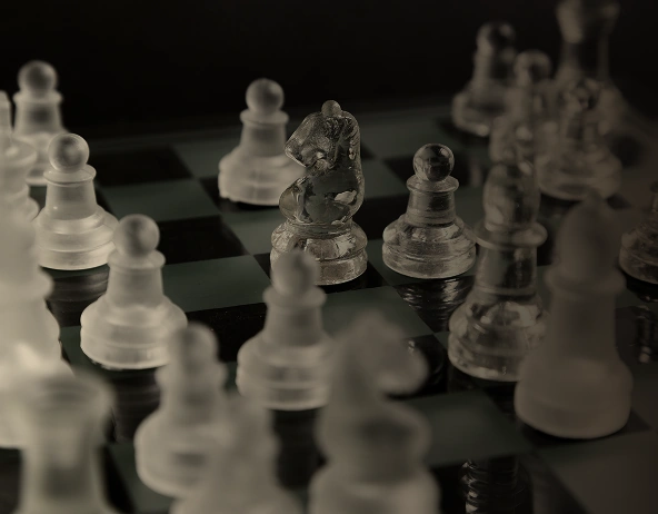 Glass chess pieces on board with knight in focus, representing strategy and decision making