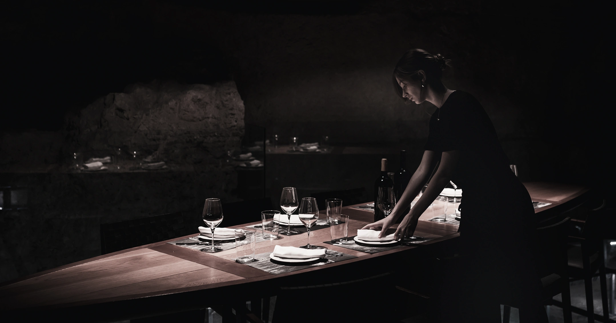 Moody restaurant interior with staff setting table for fine dining experience