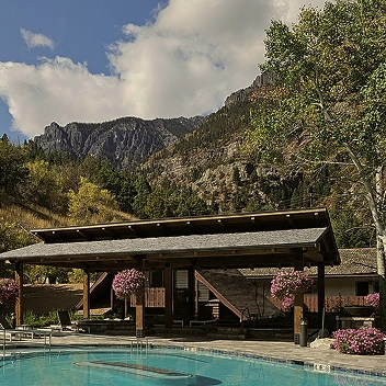 Outdoor pool at mountain resort with wooden lodge and scenic landscape