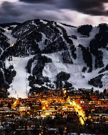 Aspen mountain at night with illuminated town and snowy ski slopes