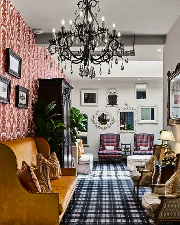 Vintage hotel lounge with chandelier, patterned wallpaper, classic furniture, and checkered carpet