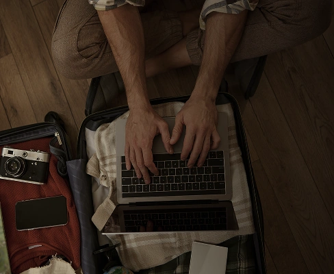 Person using laptop inside suitcase while packing for travel